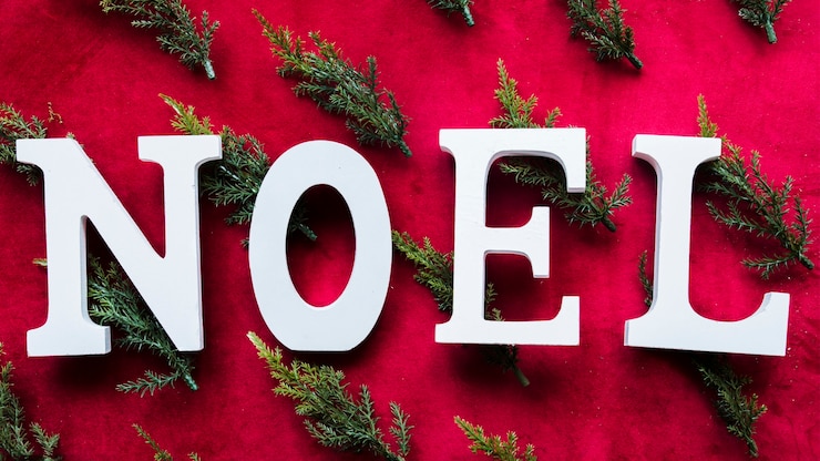 Foto gratuito título de noel entre ramas de arborvitae.