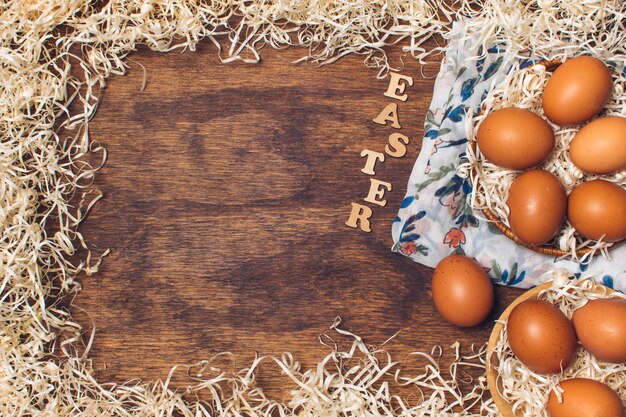 Título de Pascua cerca de los huevos de gallina en cuencos sobre material floreado entre la malla a bordo