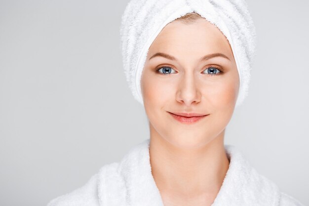 Toalla de baño de mujer bonita rubia sobre cabello mojado