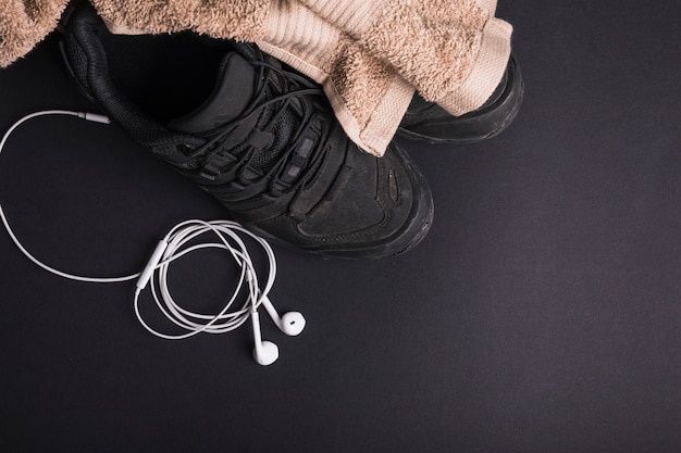 Toalla marrón en los pares de zapatos con el teléfono blanco del oído en fondo negro