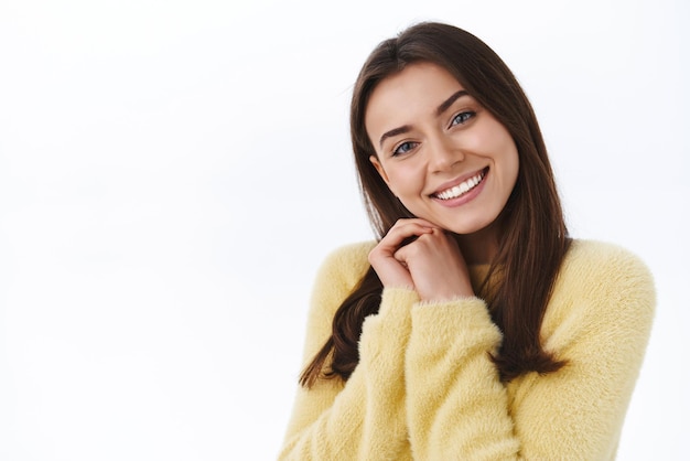 Tocada tierna novia femenina sintiéndose conmovedora y encantada mirando el hermoso regalo suspirando romántico sonriendo cabeza inclinada en las palmas contemplar la hermosa escena de pie fondo blanco