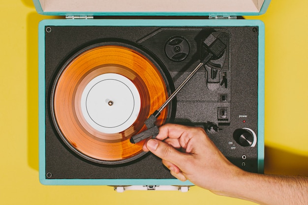 Tocadiscos vintage con una mano y disco de vinilo naranja