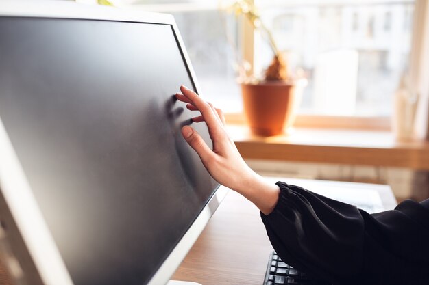 Tocando la pantalla en blanco. Mujer joven caucásica en traje de negocios trabajando en la oficina