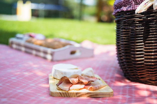 Tocino y queso en una tabla de cortar sobre la tela en el picnic