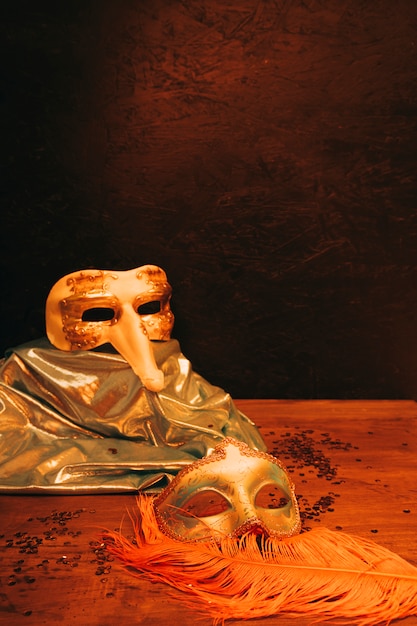 Todavía vida de la máscara veneciana del carnaval con las plumas contra fondo texturizado oscuro