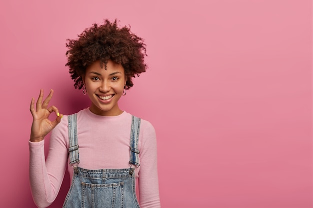 Todo está bien. La mujer sonriente de piel oscura tiene todo bajo control, da una respuesta positiva, recomienda un buen producto, se asegura de que todo va bien, le gusta algo, se ve con alegría, se para en el interior