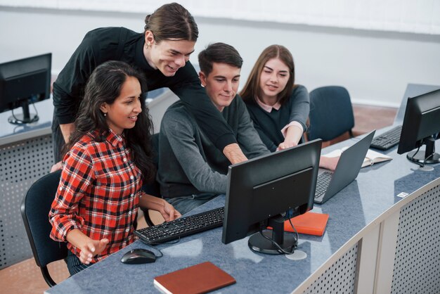 Todo será genial. Grupo de jóvenes en ropa casual que trabajan en la oficina moderna