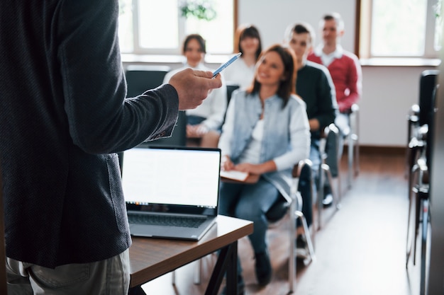 Todos sonríen y escuchan. Grupo de personas en conferencia de negocios en el aula moderna durante el día