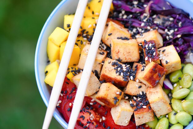 Tofu vegetariano poke bowl sobre mesa de madera al aire libre