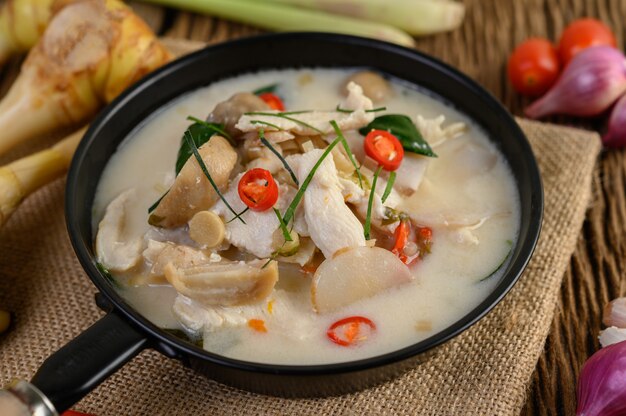 Tom Kha Kai en una sartén con hojas de lima kaffir, hierba de limón, cebolla roja, galanga y chile.