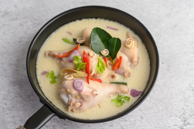 Tom Kha Kai en una sartén con hojas de lima kaffir, hierba de limón, cebolla roja, galanga y chile.