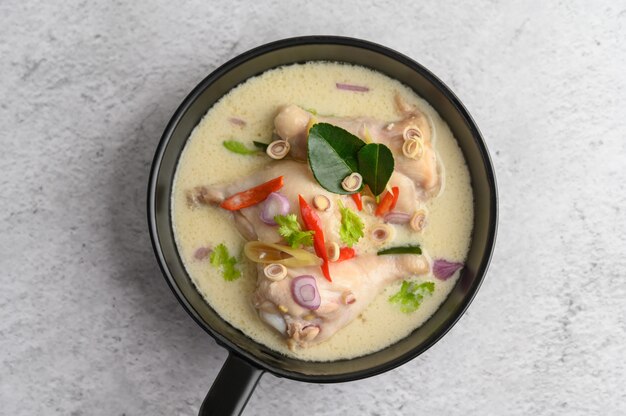 Tom Kha Kai en una sartén con hojas de lima kaffir, hierba de limón, cebolla roja, galanga y chile.