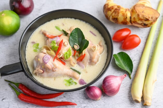 Tom Kha Kai en una sartén con hojas de lima kaffir, hierba de limón, cebolla roja, galanga y chile.