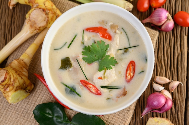 Foto gratuita tom kha kai en un tazón con hojas de lima kaffir, hierba de limón, cebolla roja, galanga y chile.