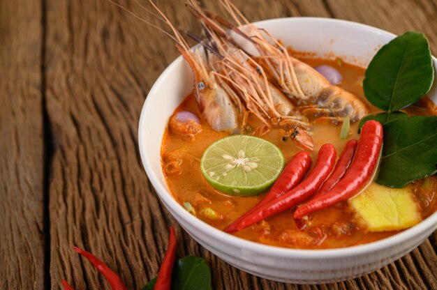 Tom Yum Kung Thai sopa picante de camarones con hierba de limón, limón, galanga y chile en mesa de madera, comida de Tailandia