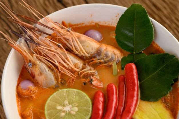 Tom Yum Kung Thai sopa picante de camarones con hierba de limón, limón, galanga y chile en mesa de madera, comida de Tailandia