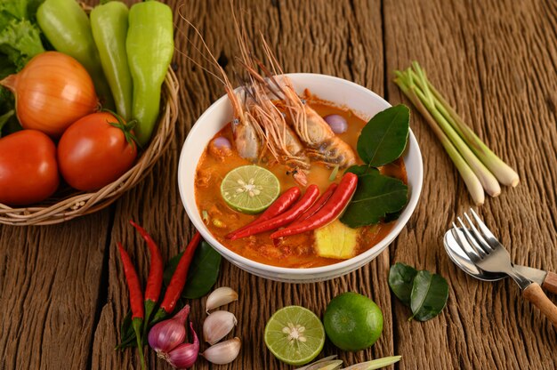 Tom Yum Kung Thai sopa picante de camarones con hierba de limón, limón, galanga y chile en mesa de madera, comida de Tailandia