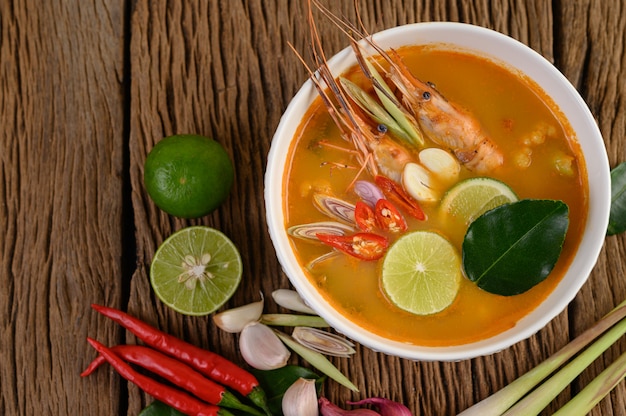 Tom Yum Kung Thai sopa picante de camarones con hierba de limón, limón, galanga y chile en mesa de madera, comida de Tailandia