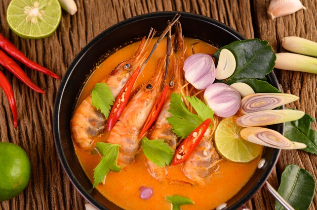 Tom Yum Kung Thai sopa picante de camarones con hierba de limón, limón, galanga y chile en mesa de madera, comida de Tailandia