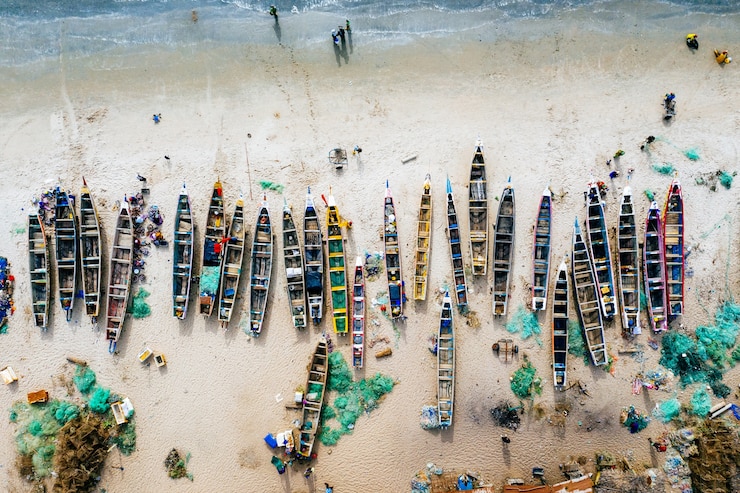 Foto gratuito toma aérea aérea de barcos de diferentes colores en una playa de arena con el mar cerca