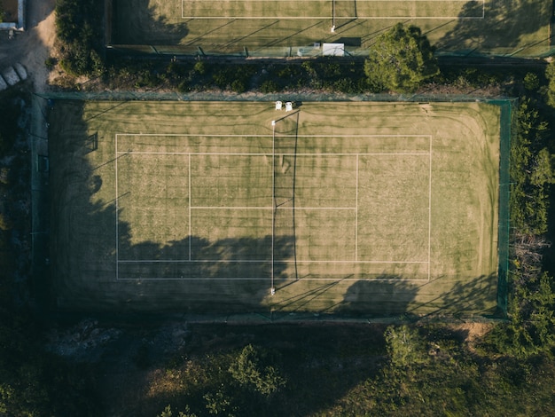 Toma aérea de una cancha de tenis rodeada de árboles