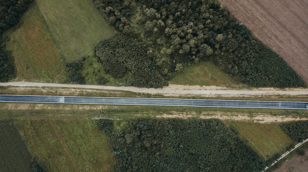 Toma aérea de una carretera en construcción rodeada de campos cultivados en el distrito de Brcko