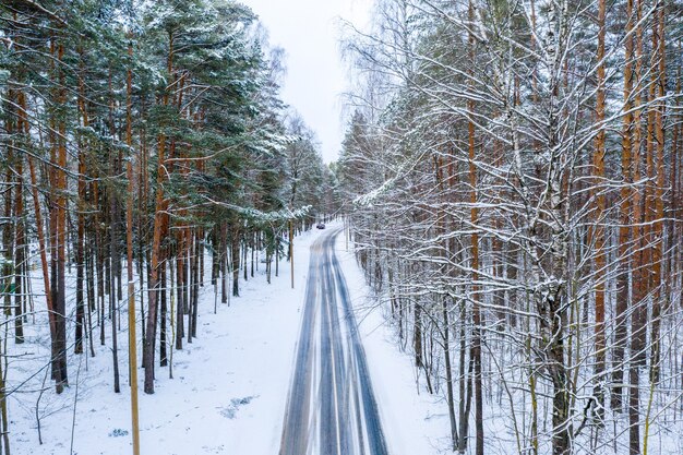 Toma aérea de la carretera de invierno a través del bosque