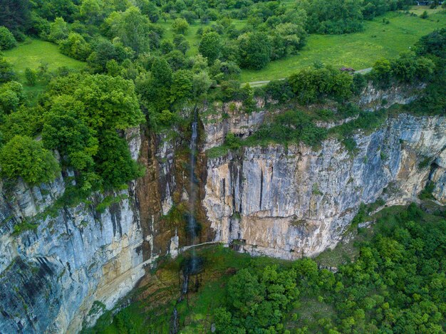 Toma aérea de una cascada en la hermosa montaña cubierta de árboles