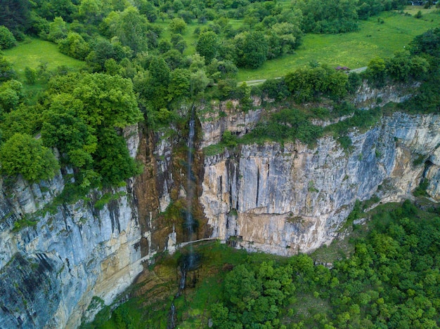 Toma aérea de una cascada en la hermosa montaña cubierta de árboles