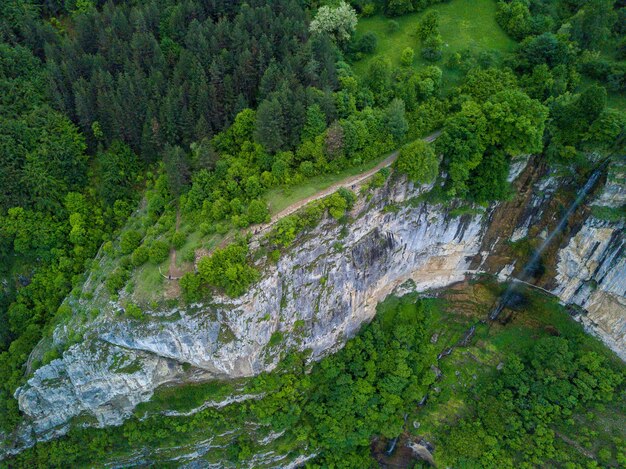 Toma aérea de una cascada en la hermosa montaña cubierta de árboles