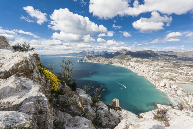 Toma aérea de una ciudad a lo largo de la costa de la bahía con nubes blancas en el cielo azul