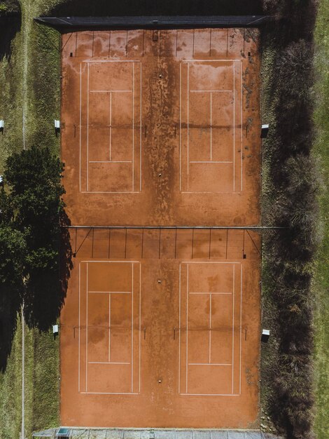 Toma aérea de cuatro campos deportivos conectados y rodeados por un césped verde