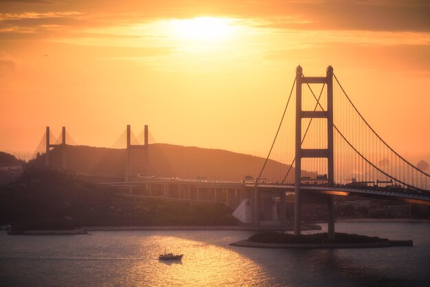 Toma aérea de edificios de la ciudad, colinas y un puente sobre un río al atardecer