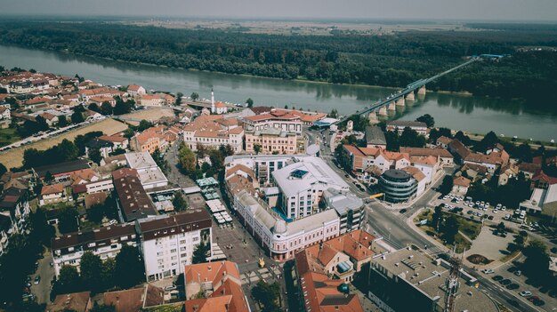 Toma aérea de edificios de la ciudad con un puente sobre el río cerca de árboles y plantas