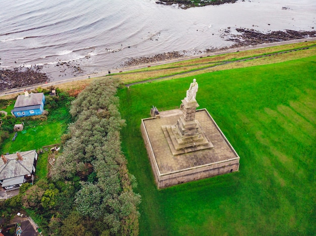 Toma aérea de una estatua en el valle verde cerca del mar