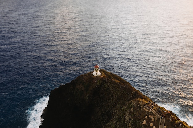 Foto gratuita toma aérea de un faro en la cima del acantilado en mar abierto