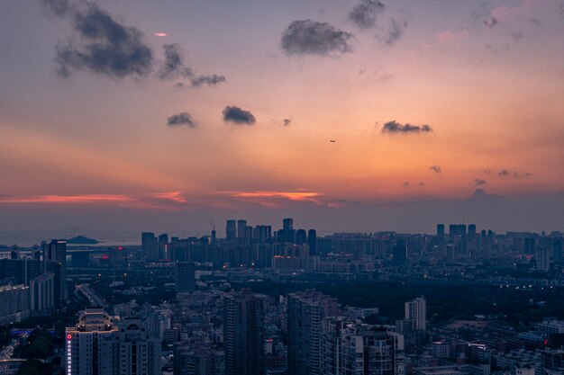 Toma aérea de una gran ciudad bajo un cielo nublado azul anaranjado al atardecer