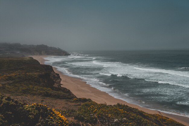 Toma aérea de la hermosa costa arenosa del mar con un cielo gris oscuro