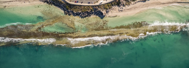 Foto gratuita toma aérea de las hermosas olas del mar que se encuentran con la playa