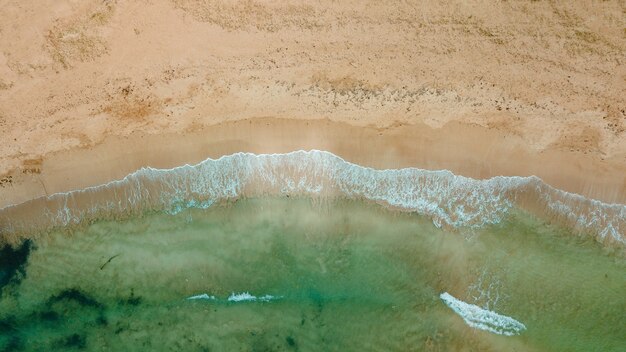 Toma aérea impresionante del océano con una playa de arena