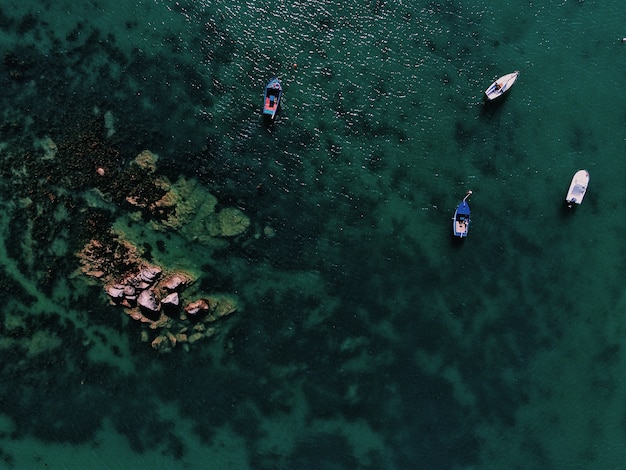 Foto gratuita toma aérea de un mar con barcos cerca de una roca durante el día