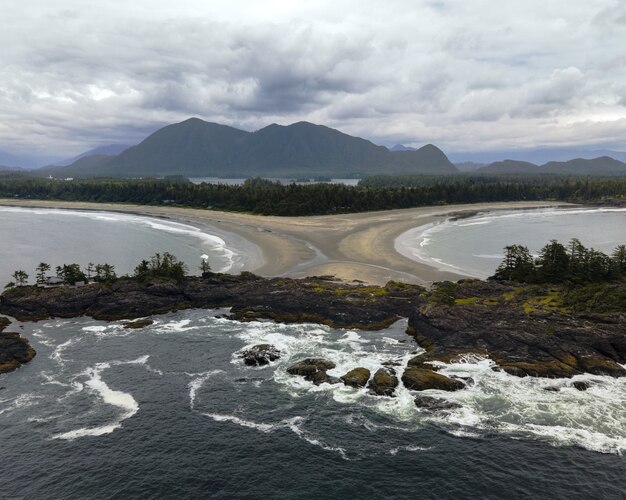 Toma aérea de un mar rodeado de rocas con montañas detrás