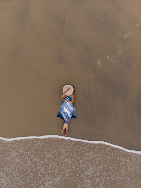 Foto gratuita toma aérea de una mujer asiática acostada en una playa de arena