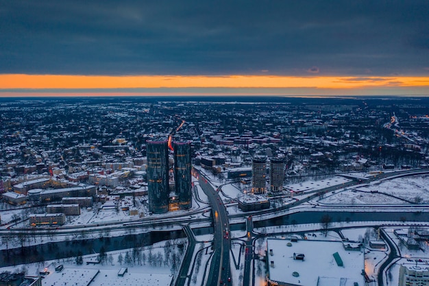 Toma aérea de la nevada Riga, Letonia durante el atardecer naranja