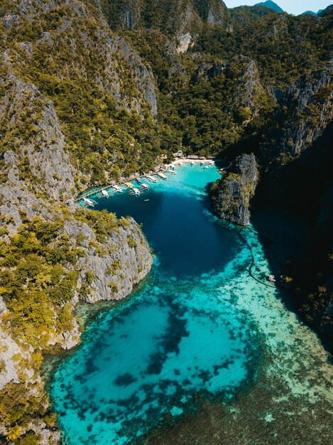 Toma aérea del océano rodeado de hermosas montañas cubiertas de verdes