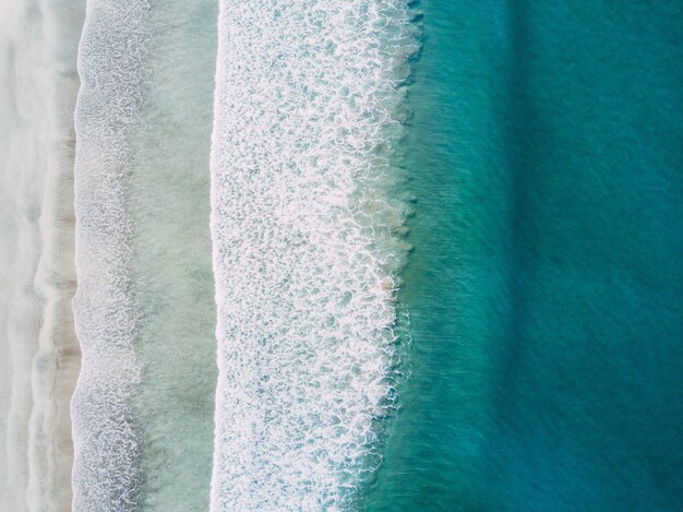 Toma aérea de las olas del mar golpeando la orilla durante el día