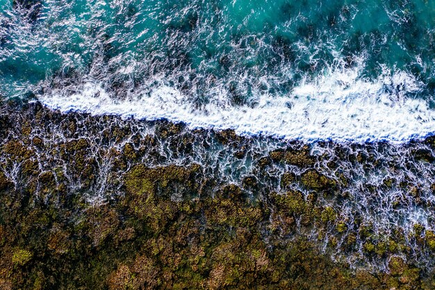 Toma aérea de una orilla rocosa con olas espumosas