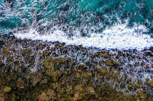 Toma aérea de una orilla rocosa con olas espumosas