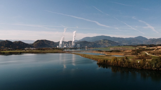 Toma aérea de un paisaje rodeado de montañas y lagos con desastre industrial