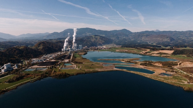 Toma aérea de un paisaje rodeado de montañas y lagos con desastre industrial